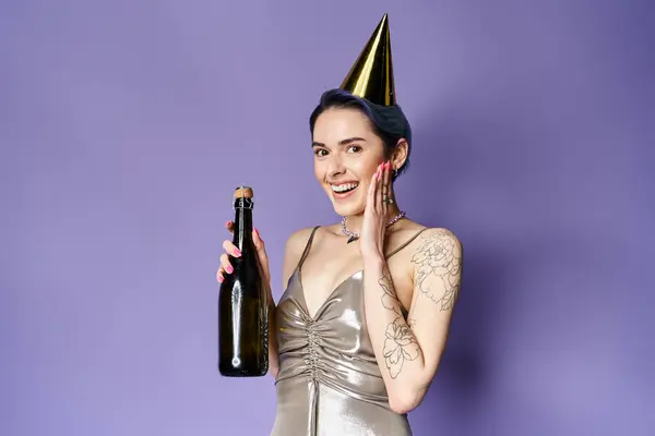 A young woman with short blue hair wearing a silver party dress, holding a bottle of champagne and a festive party hat. — Fotografia de Stock