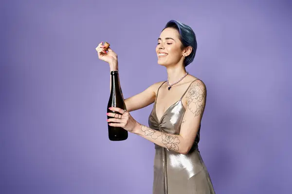 Young woman with short blue hair posing elegantly in a silver dress, holding a bottle of champagne. — Fotografia de Stock