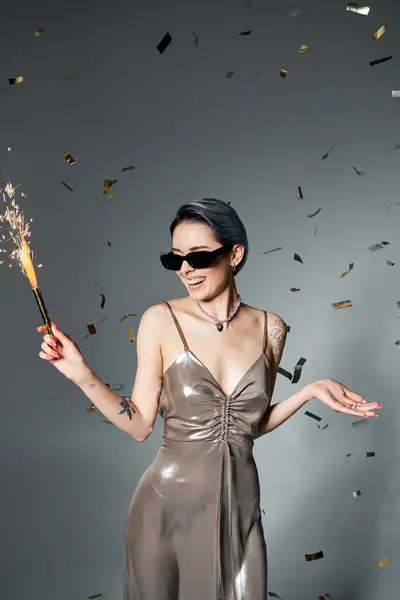 Young woman in a silver dress with blue hair holding a sparkler in a stylish and festive pose. — Stock Photo