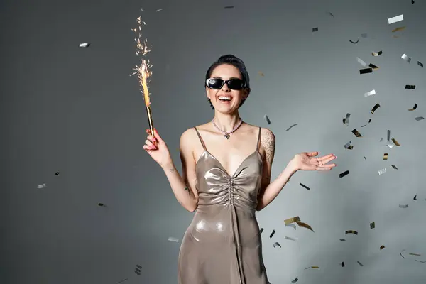 Young woman with blue hair poses in silver dress, holding sparkler. — Fotografia de Stock