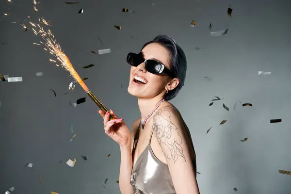 Stylish woman with short blue hair wearing sunglasses, holding sparkler. — Stock Photo