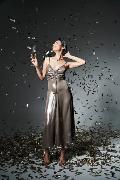 Young woman exudes grace in silver dress while holding champagne glass. — Stock Photo