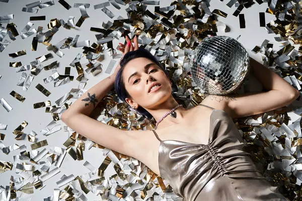 A stylish young woman with blue hair dazzles in a silver dress while holding a reflective disco ball. — Fotografia de Stock