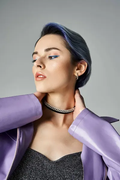 A young woman with striking blue hair elegantly poses in a chic purple jacket in a studio setting. — Stock Photo