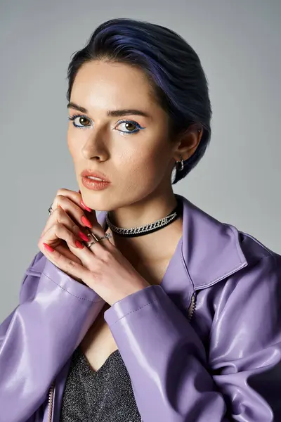 A fashionable, young woman with short dyed hair poses in a stylish purple jacket in a studio setting. - foto de stock