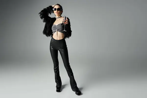 A stylish young woman with short dyed hair striking a pose in leather pants and a crop top. She exudes confidence and edginess. — Fotografia de Stock