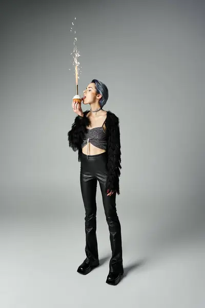 Edgy young woman with dyed hair and stylish clothes licking cupcake — стоковое фото