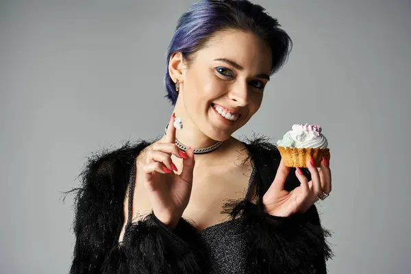 A young woman with blue hair holding a delicious cupcake in a studio setting, exuding a festive birthday vibe. — стокове фото