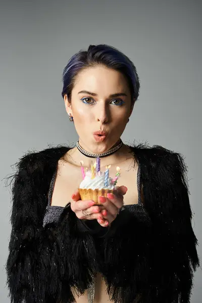A pretty young woman with short dyed hair poses in stylish attire, holding a delicious cake in her hand. — Fotografia de Stock