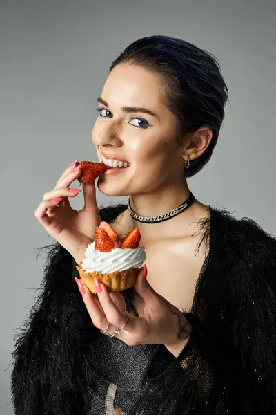 Young woman enjoying a sweet cupcake with fresh strawberries — стоковое фото