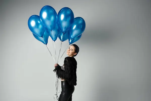 A stylish young woman with short dyed hair holds a bunch of blue balloons, exuding joy and celebration. — Fotografia de Stock
