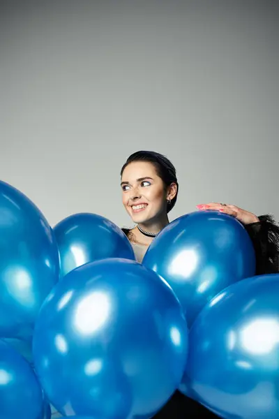 A stylish birthday girl with short dyed hair delicately holds a bunch of vibrant blue balloons. — Stock Photo