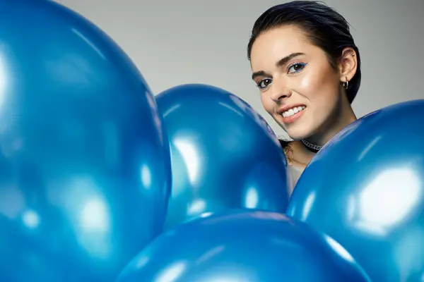 A stylish young woman with short dyed hair is elegantly holding a bunch of blue balloons with a joyful expression. — Stock Photo