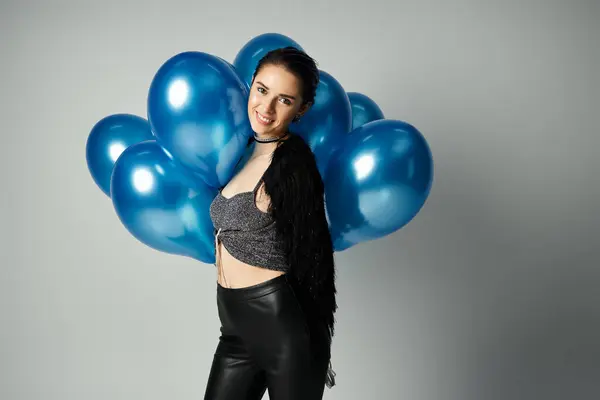 A stylish young woman with short dyed hair poses surrounded by a bunch of vibrant blue balloons. — Fotografia de Stock