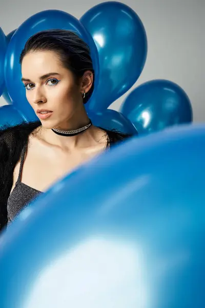 A young woman with short dyed hair poses elegantly in front of a bunch of blue balloons. — Stock Photo