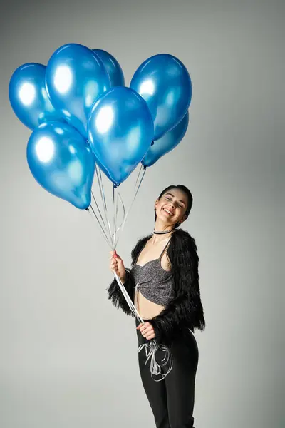 A stylish young woman with short dyed hair poses happily while holding a bunch of blue balloons. — Fotografia de Stock