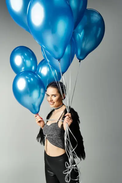 A stylish young woman with short dyed hair holding a bunch of blue balloons. — Stock Photo