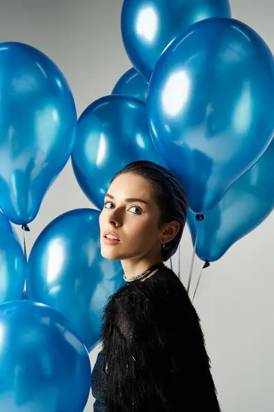 Young woman with dyed hair stands in front of a group of blue balloons, exuding elegance and style. — Photo de stock