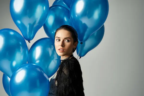 A stylish young woman with short dyed hair holding a bunch of blue balloons in a studio setting. — Stock Photo