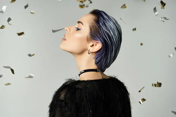 A young woman with eye-catching blue hair stands confidently in front of a backdrop of confetti. — Foto stock