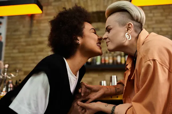 Two women deeply kissing in a dimly lit bar. — Photo de stock