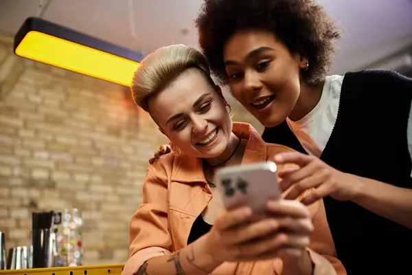 Two diverse women engaged in a conversation while looking at a cell phone. — Photo de stock