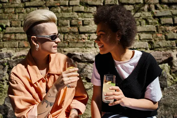 Deux femmes belles et diversifiées sont assises à proximité, absorbées par la conversation dans un café. — Photo de stock