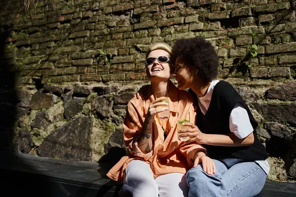 Duas mulheres diversas, desfrutando de um encontro em um café acolhedor, sentado lado a lado. — Fotografia de Stock