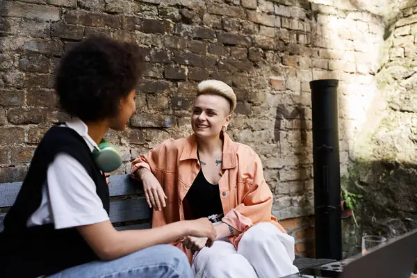 Two women sitting on a bench, engaged in conversation. — Stock Photo