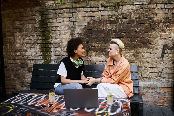 A diverse couple of lesbians engrossed in conversation on a bench. — Stock Photo
