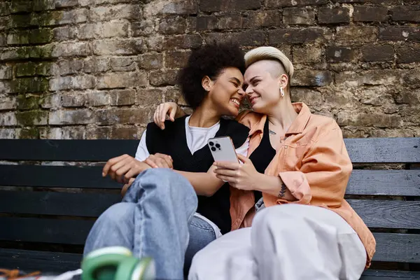 A diverse, beautiful couple of lesbians enjoy a tranquil moment together on a wooden bench. — Photo de stock