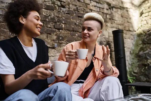 Diverse lesbian couple enjoying a date at a cafe, sitting closely together. — Stock Photo