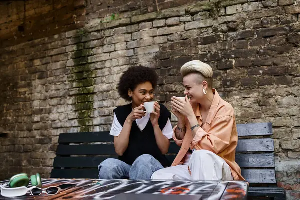 Due donne diverse si godono un pasto su una panchina. — Foto stock