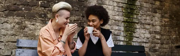 A diverse couple of women enjoying a moment of connection while sitting on a bench. — Stock Photo