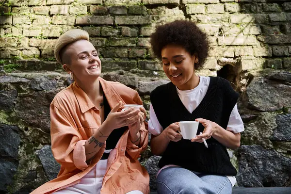 Un par de lesbianas diversas y hermosas disfrutando de una cita en un acogedor café. - foto de stock