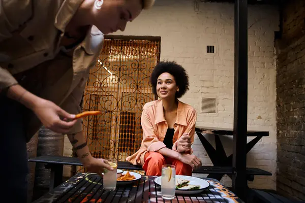 Две стильные женщины наслаждаются едой за столом. — стоковое фото