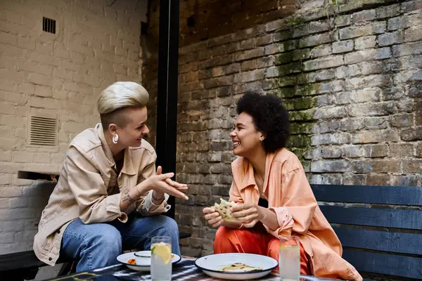 Two diverse women engrossed in a lively conversation at a cafe table. — Photo de stock