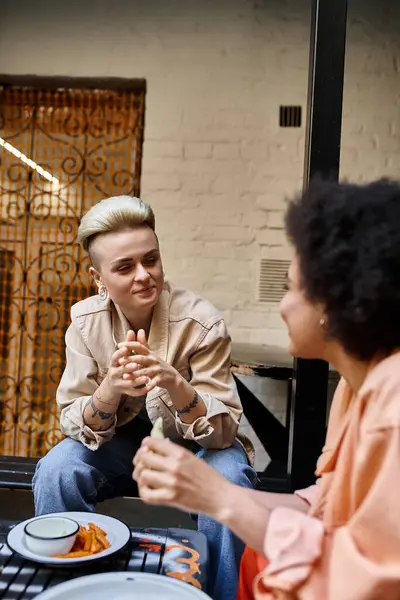 Two women engaged in a lively conversation at a cafe table. — Stock Photo