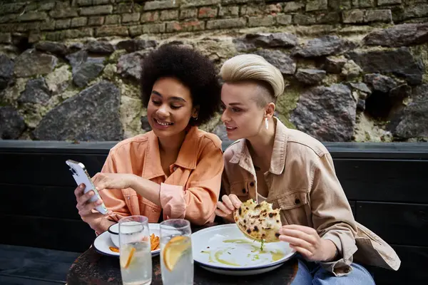 Разнообразная и красивая пара лесбиянок обедают вместе за уютным столиком в кафе. — стоковое фото