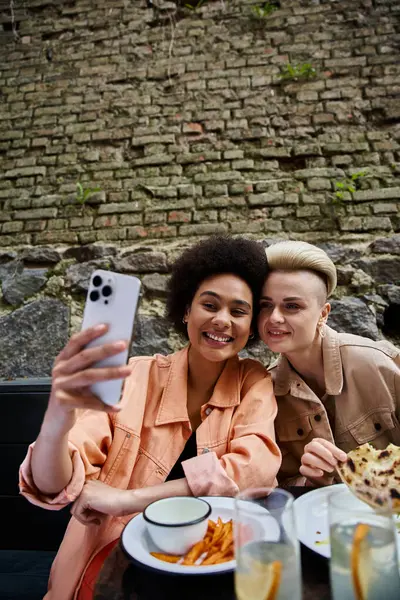 Two women at a cafe table, taking a selfie. — Stock Photo