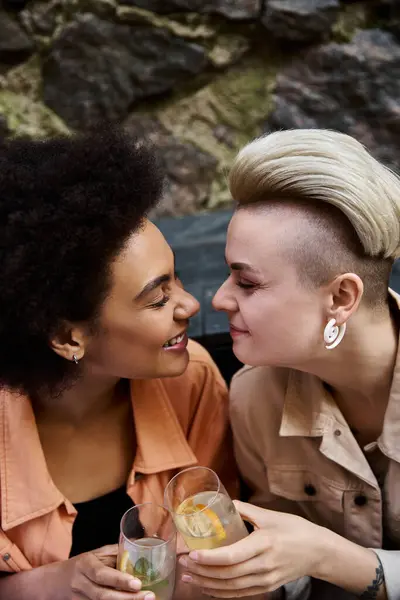 Deux femmes différentes et belles s'assoient étroitement ensemble dans un café confortable, profondément dans la conversation. — Photo de stock