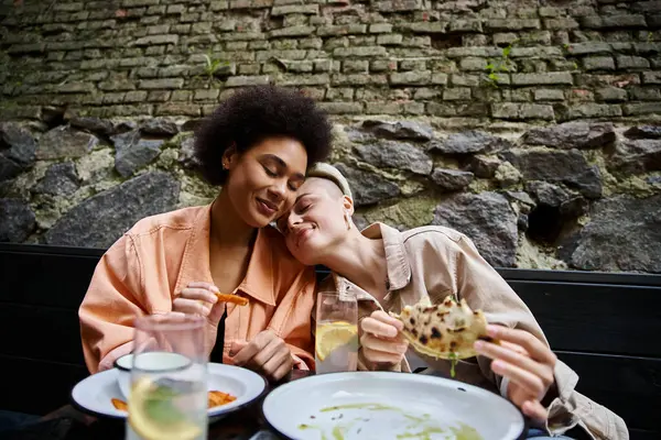 Diverse, beautiful couple of women sitting at a table, enjoying a meal together. — Stock Photo