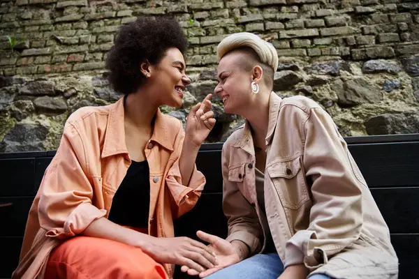 Un couple diversifié de lesbiennes élégantes partagent un moment de proximité dans un café confortable. — Photo de stock