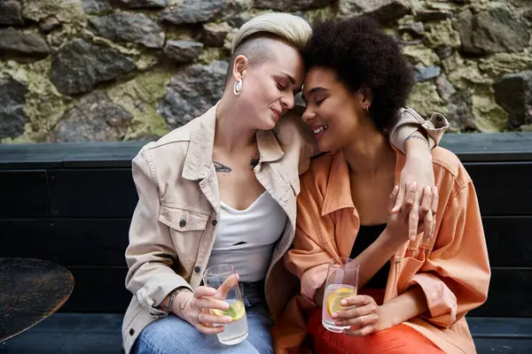 Two diverse women, a beautiful couple, sit closely on a bench. — Photo de stock