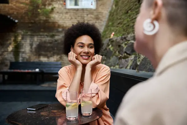 A woman sits at a table, calmly looking lovingly and cheerfully at her female partner. — Stock Photo