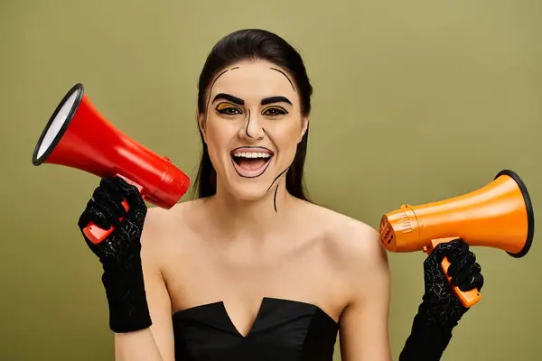Brünette Frau in einem eleganten schwarzen Kleid hält ein leuchtend rotes und orangefarbenes Megafon in der Hand. — Stockfoto