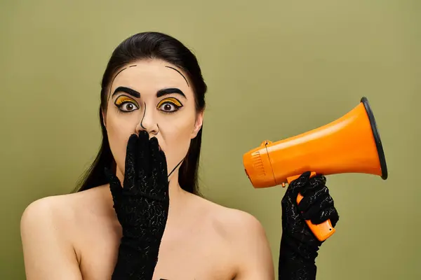 Brunette woman with pop art makeup wears black gloves while holding an orange and black megaphone. — Stock Photo