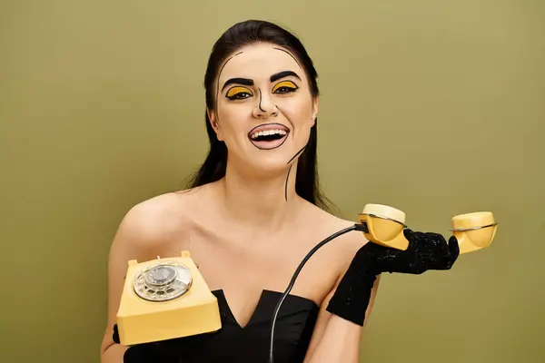 Stilvolle Brünette in schwarzem Kleid und Handschuhen, verkörpert Vintage-Glamour, während sie ein leuchtend gelbes Telefon in der Hand hält. — Stockfoto