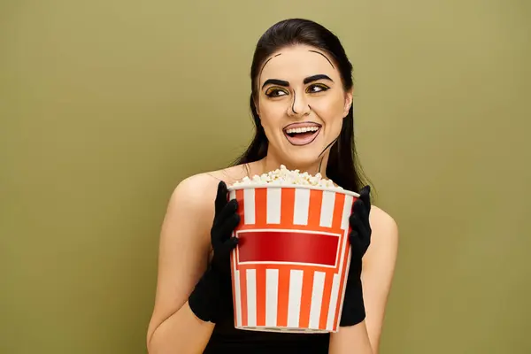 A woman with makeup in a pop art style holds a bucket of popcorn in front of her face. — Stock Photo