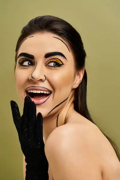 Brunette woman in black gloves hides behind a fake face in pop art style makeup. — Stock Photo